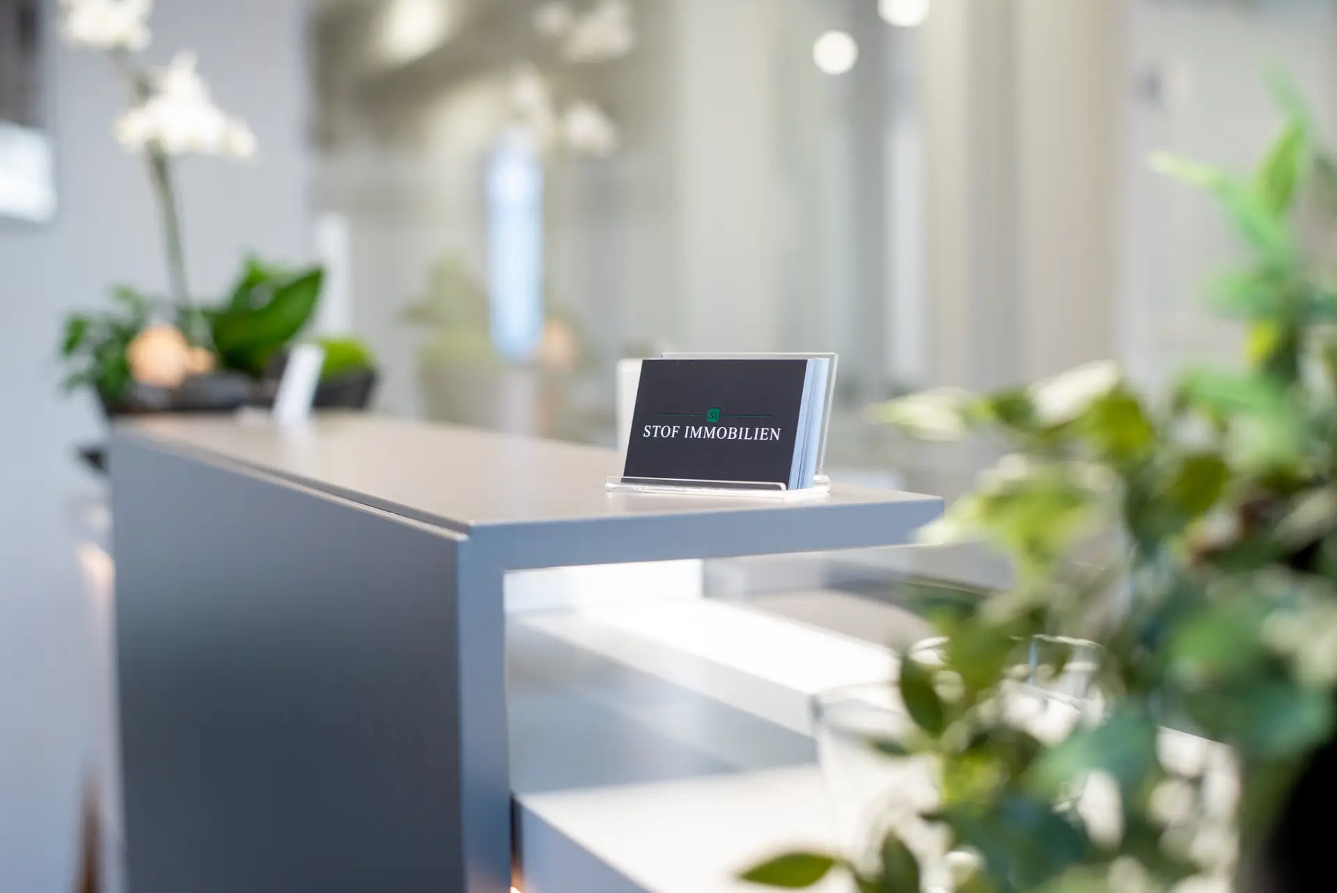 Visitenkarten von Stof Immobilien im Vordergrund mit Marcel Stof, Inhaber, im Hintergrund beim Telefonieren im Maklerbüro in Laichingen