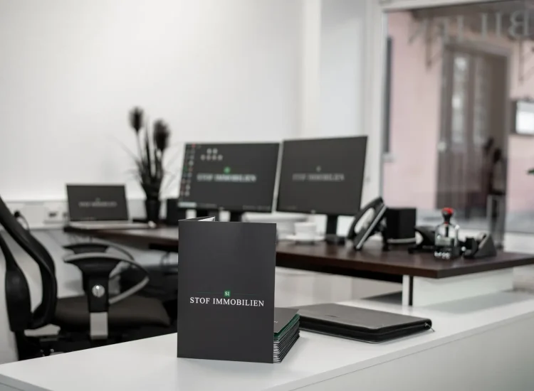 Immobilienexposé-Mappe im Fokus auf dem Schreibtisch im Maklerbüro von Stof Immobilien in Laichingen – professionelle Immobilienpräsentation